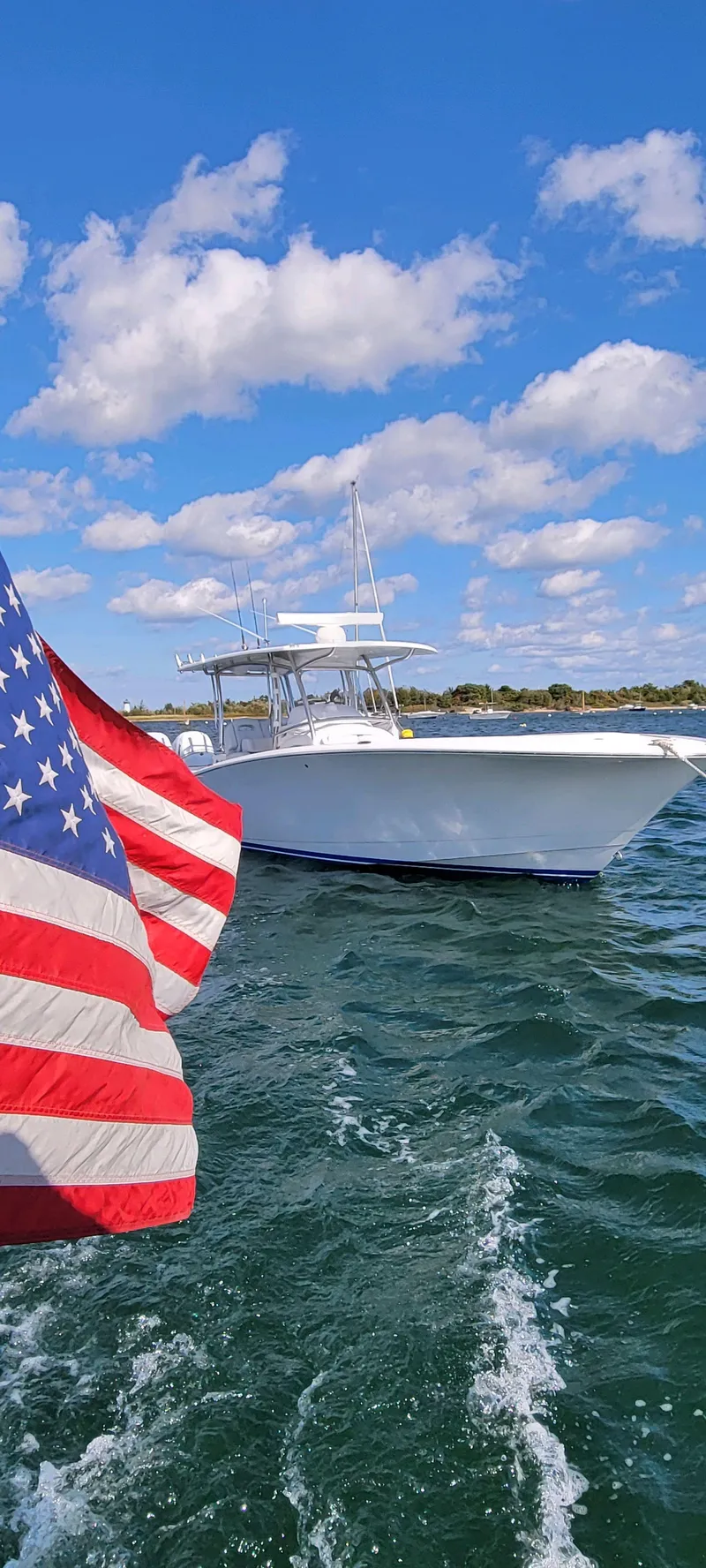 Slide: The Image of 2023 Mag Bay 33 CC boat on water with American flag in foreground. - 14