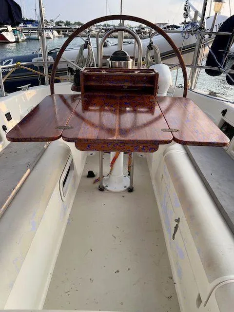 Slide: The Image of 1986 Pearson 36 sailboat cockpit with wooden table and steering wheel, docked at marina. - 11