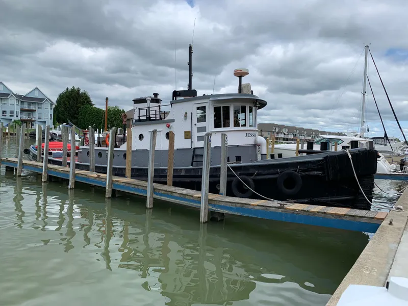 The Image of Vintage 1936 Bow Steel tugboat docked at a marina under cloudy skies. - 0
