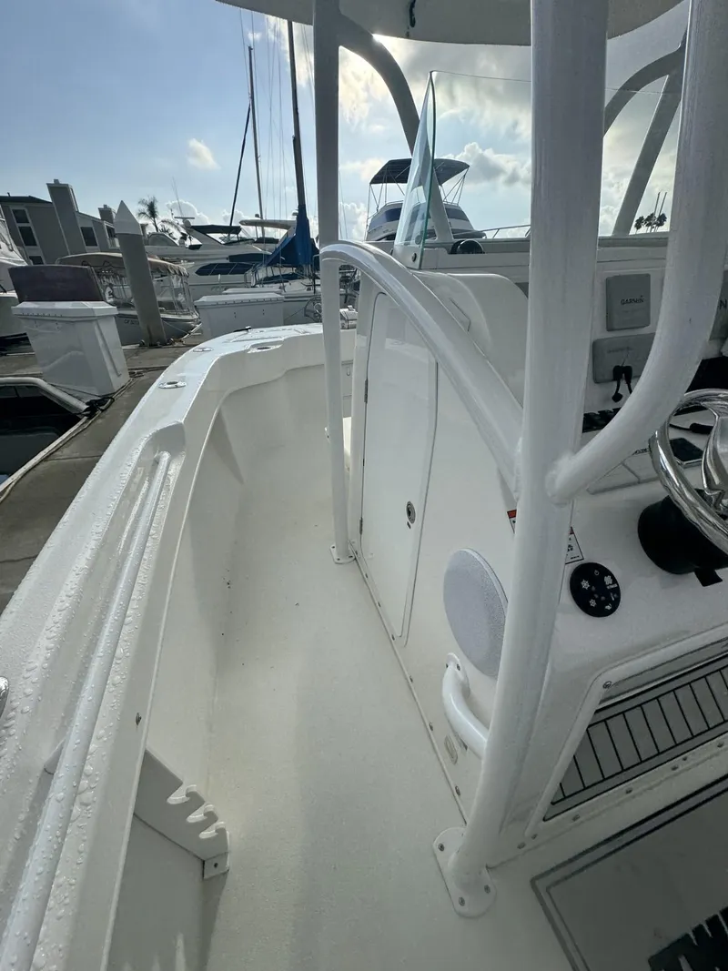 Slide: The Image of 2021 Twin Vee Catamaran boat interior, featuring sleek white design and modern controls at a marina. - 11