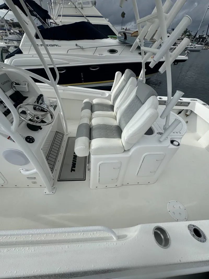 Slide: The Image of 2021 Twin Vee Catamaran interior with white seating and steering wheel, docked at marina. - 3