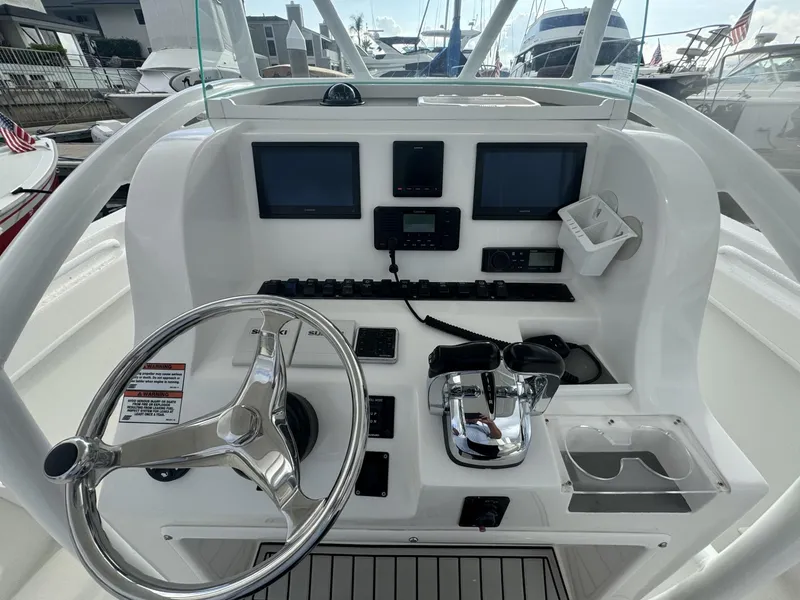 Slide: The Image of 2021 Twin Vee Catamaran helm with steering wheel, dual screens, and control panel. - 5