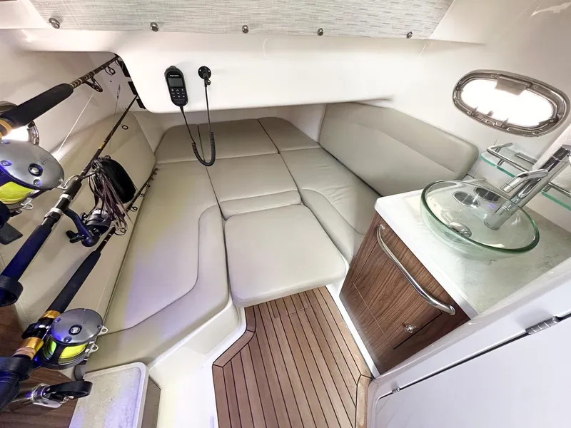 Slide: The Image of 2021 Boston Whaler 380 Outrage cabin interior with fishing rods and compact kitchenette. - 16