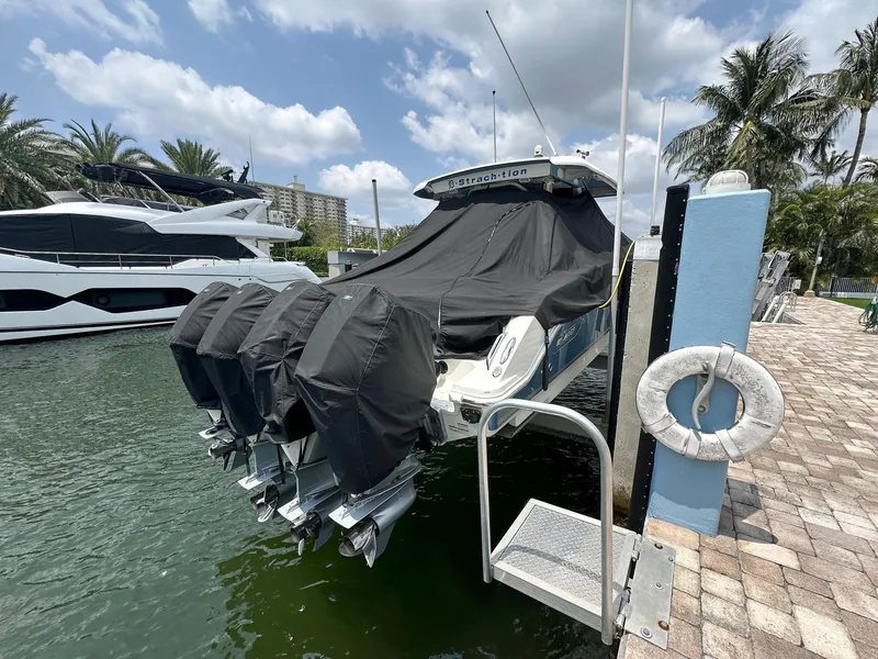 Slide: The Image of Boston Whaler 380 Outrage 2021 docked, covered, with four engines, under a partly cloudy sky. - 18
