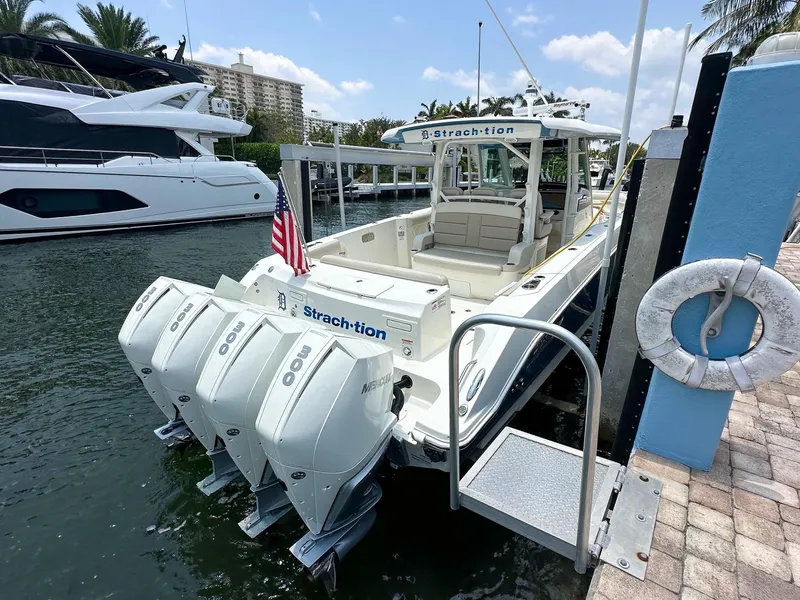 Slide: The Image of 2021 Boston Whaler 380 Outrage docked, featuring triple outboard engines and American flag. - 19