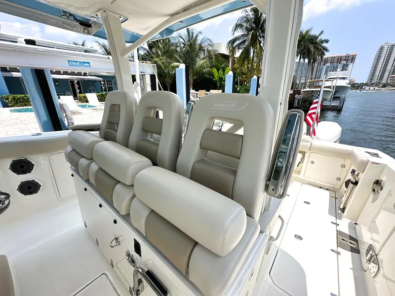 Slide: The Image of 2021 Boston Whaler 380 Outrage boat interior with plush seating, docked near palm trees. - 5