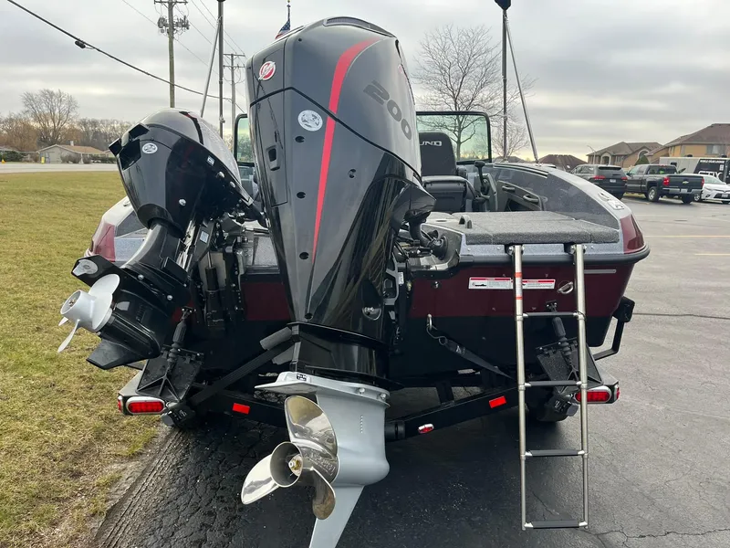 Slide: The Image of 2025 Lund 189 Tyee GL boat with dual outboard motors and ladder, parked on pavement. - 3