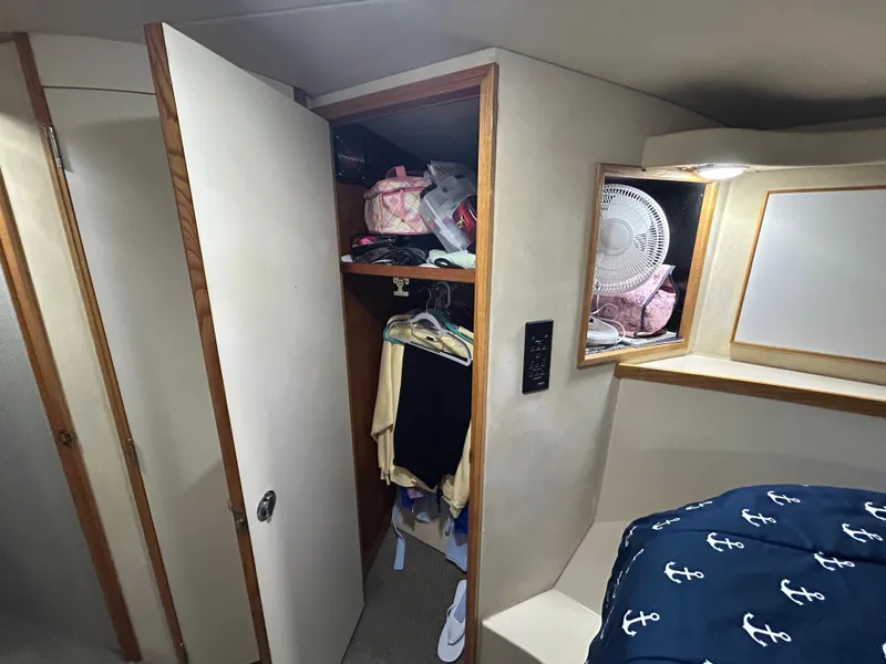 Slide: The Image of Interior of 1988 Bertram 43 Convertible with open closet and nautical-themed bedding. - 11