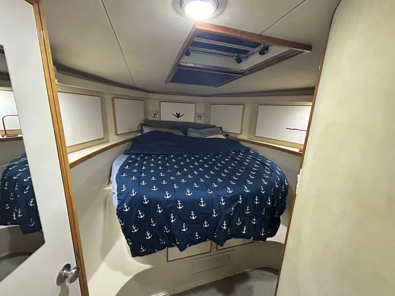 Slide: The Image of 1988 Bertram 43 Convertible cabin with anchor-patterned bedding and overhead hatch. - 13