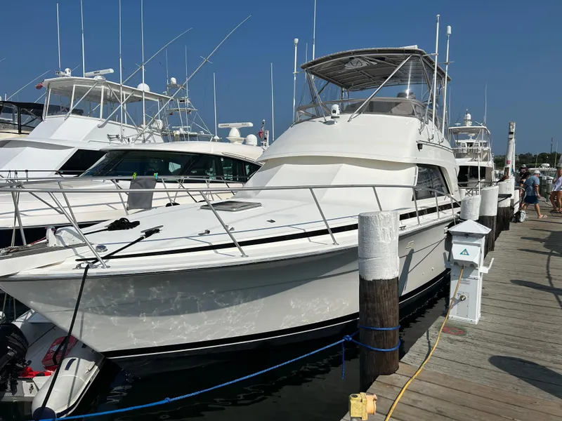 Slide: The Image of 1988 Bertram 43 Convertible yacht docked at marina under clear blue sky. - 2