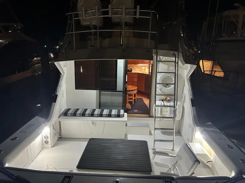 Slide: The Image of 1988 Bertram 43 Convertible yacht interior with seating and ladder, illuminated at night. - 8