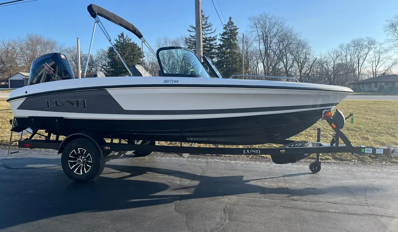 Slide: The Image of 2025 Lund 189 Tyee GL boat on trailer, parked outdoors on a sunny day. - 2
