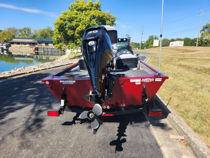 Slide: The Image of 2018 Tracker Pro 170 boat with motor, parked near a lakeside on a sunny day. - 2