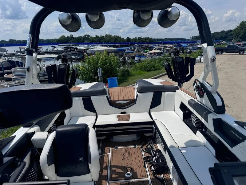 Slide: The Image of 2018 Nautique G23 boat interior with white seating and wood accents at a marina. - 10