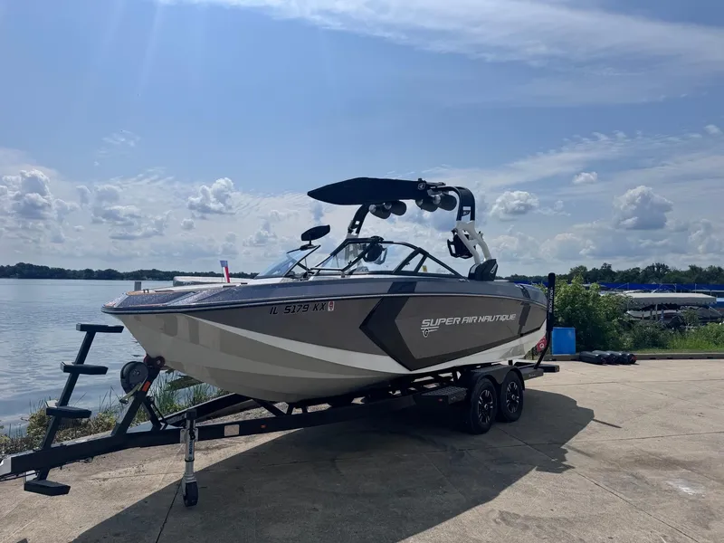 Slide: The Image of 2018 Nautique G23 boat on trailer by a lake under a cloudy sky. - 12