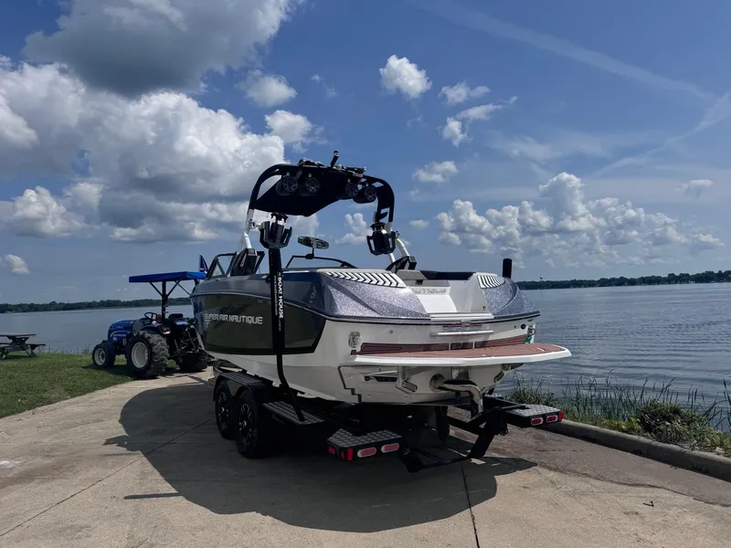 Slide: The Image of 2018 Nautique G23 boat on trailer by a lake under a cloudy sky. - 13