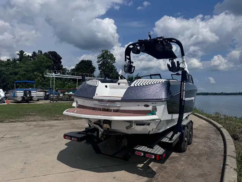Slide: The Image of 2018 Nautique G23 boat on trailer by a lake under a cloudy sky. - 14