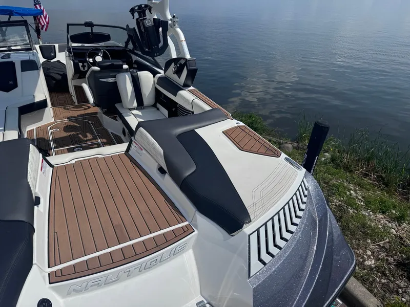 Slide: The Image of 2018 Nautique G23 boat with sleek interior and wooden deck by the water. - 4