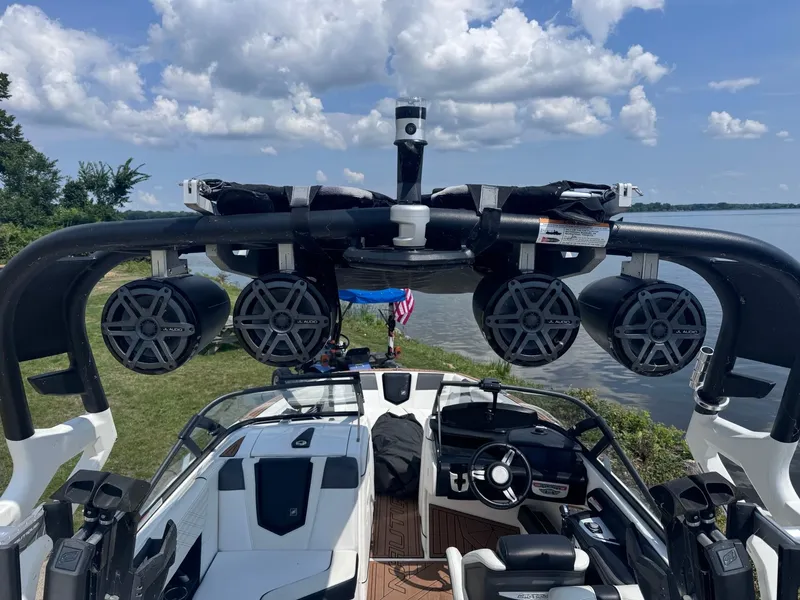 Slide: The Image of 2018 Nautique G23 boat with speakers, docked by a scenic lake under a cloudy sky. - 6