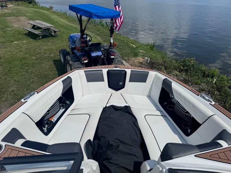 Slide: The Image of 2018 Nautique G23 boat interior near lake with tractor and American flag. - 9