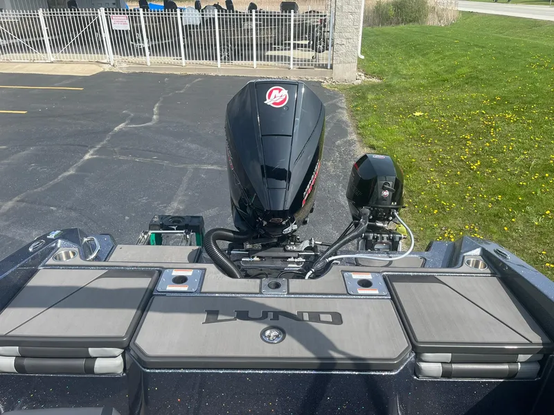 Slide: The Image of 2025 Lund 202 Pro-V GL boat with powerful outboard motor, parked on pavement. - 12