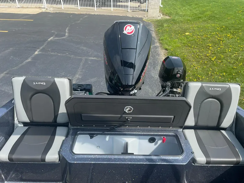 Slide: The Image of 2025 Lund 202 Pro-V GL boat with dual seats and motor, parked on pavement. - 13