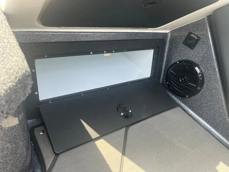 Slide: The Image of 2025 Lund 202 Pro-V GL boat interior storage compartment with speaker and sleek design. - 33