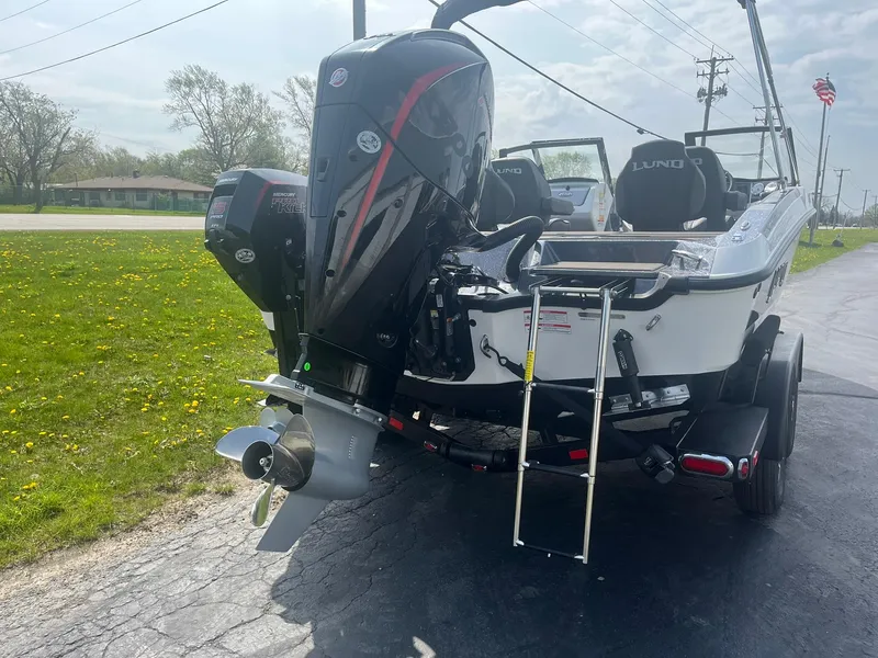 Slide: The Image of 2025 Lund 202 Pro-V GL boat with powerful outboard motor and ladder, parked on a sunny day. - 4