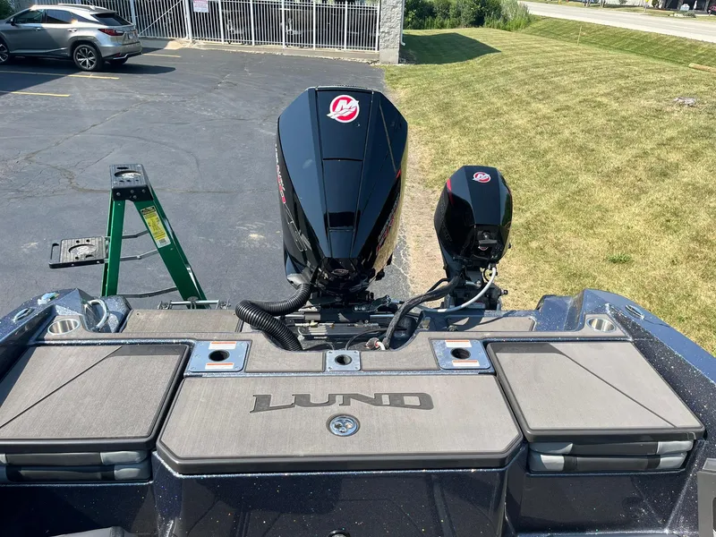 Slide: The Image of 2025 Lund 202 Pro-V GL boat with dual outboard motors, parked on pavement. - 11