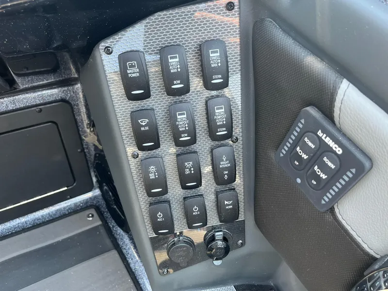 Slide: The Image of Control panel of 2025 Lund 202 Pro-V GL boat with various switches and Lenco trim tab controls. - 26