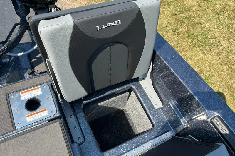 Slide: The Image of 2025 Lund 202 Pro-V GL boat seat with storage compartment, shown in outdoor setting. - 37