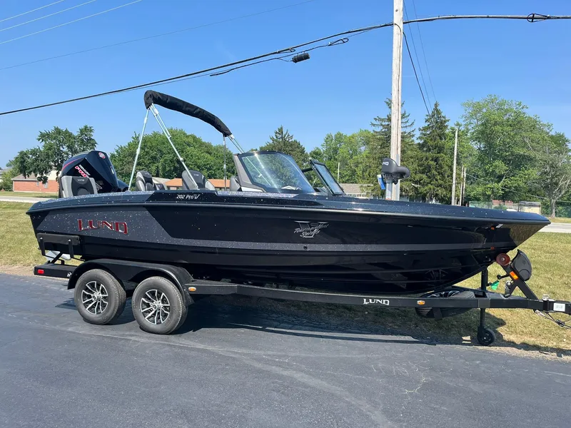 Slide: The Image of 2025 Lund 202 Pro-V GL boat on trailer, parked outdoors on sunny day. - 4