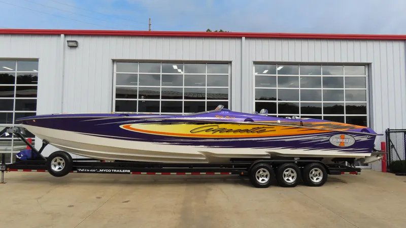 The Image of 2005 Cigarette 39' Top Gun Unlimited speedboat with vibrant graphics on a trailer. - 0