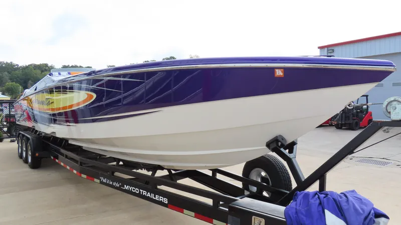 Slide: The Image of 2005 Cigarette 39' Top Gun Unlimited boat on trailer, vibrant design, parked outdoors. - 4