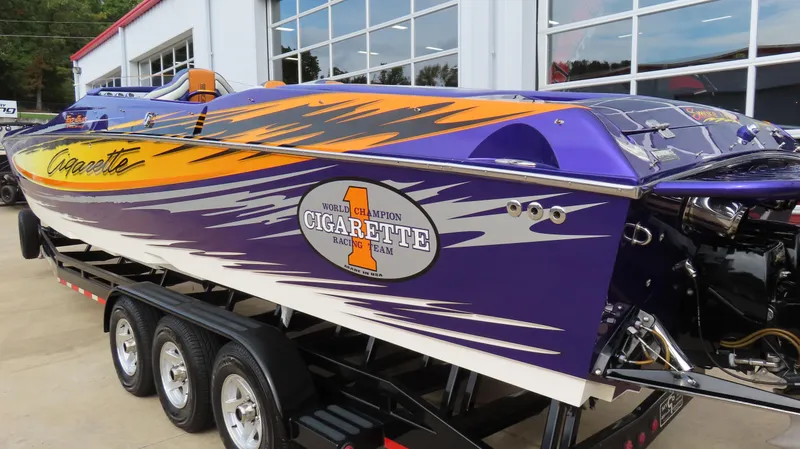 Slide: The Image of 2005 Cigarette 39' Top Gun Unlimited speedboat with vibrant purple and orange design on trailer. - 7