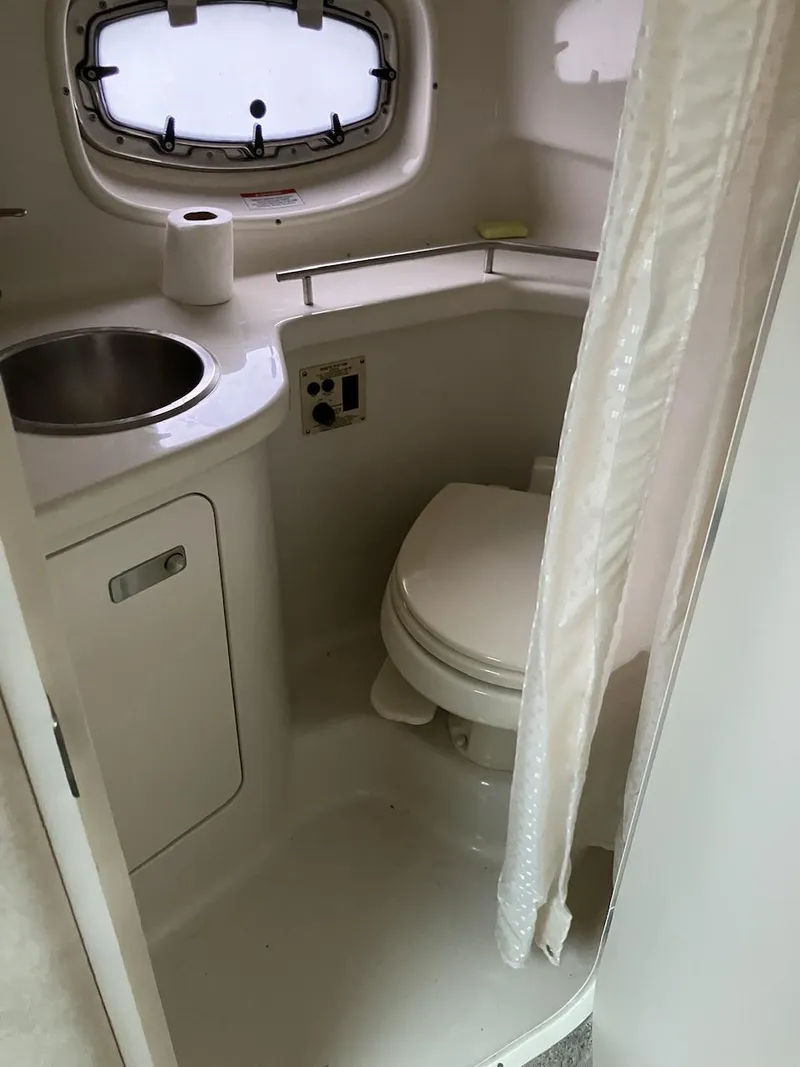 Slide: The Image of 2012 Sea Ray 280 Sundancer bathroom with sink, toilet, and porthole window. - 7