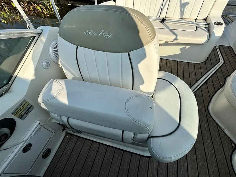 Slide: The Image of Captain's seat on 2006 Sea Ray 240 Sundancer boat, featuring white upholstery and logo. - 14
