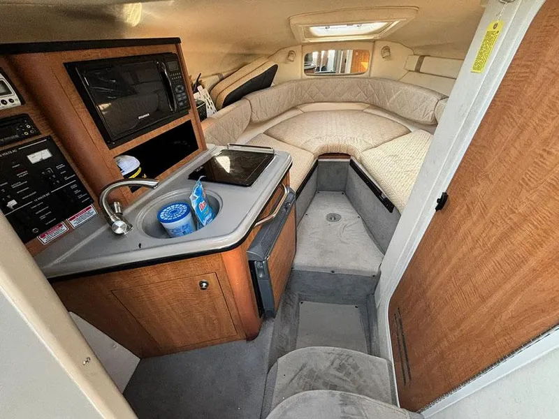 Slide: The Image of Interior of 2006 Sea Ray 240 Sundancer boat, featuring kitchenette and cozy seating area. - 17