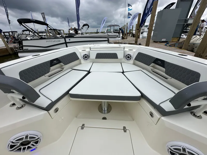Slide: The Image of 2025 Cobia 265 CC boat interior with cushioned seating and speakers at a marina. - 11