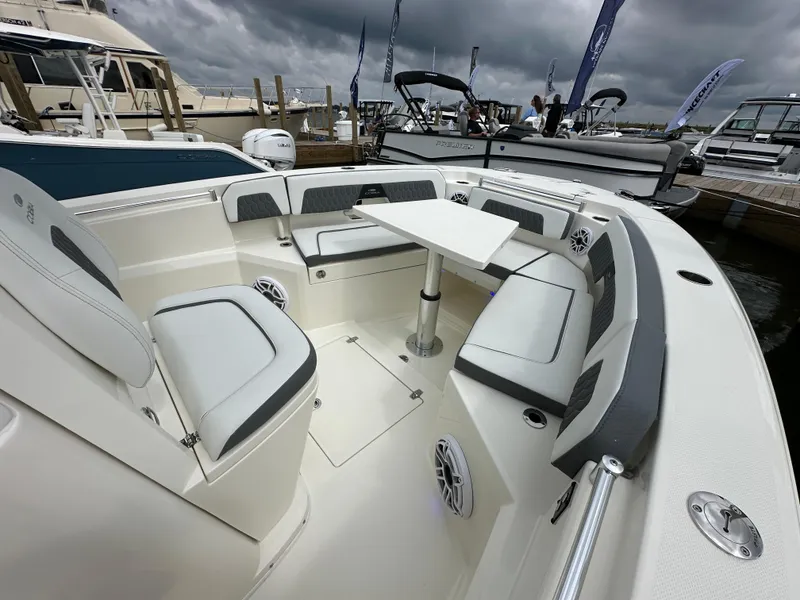Slide: The Image of 2025 Cobia 265 CC boat interior with seating and table, docked under cloudy skies. - 9