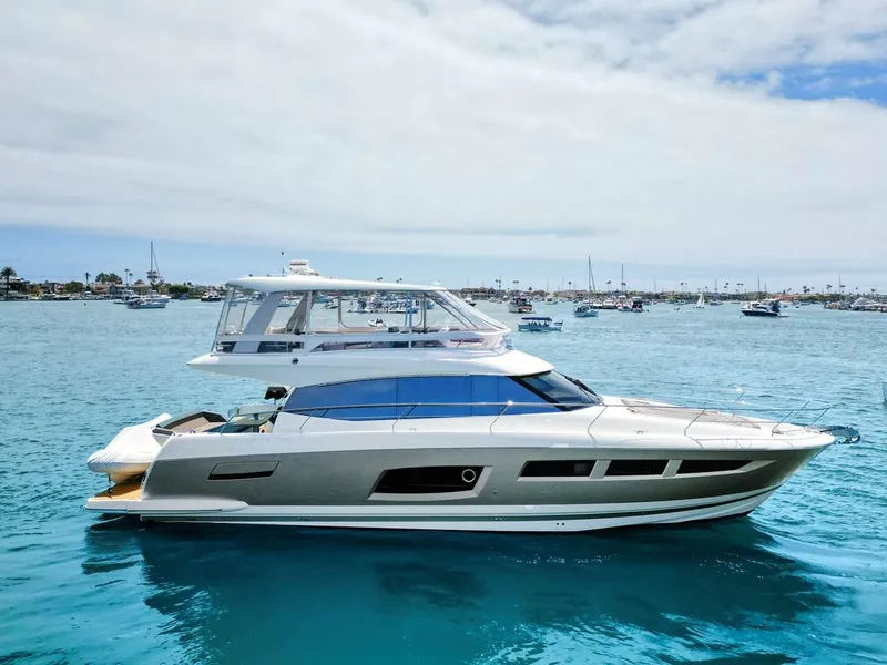Slide: The Image of 2016 Prestige 550 yacht on clear blue water, surrounded by other boats. - 1