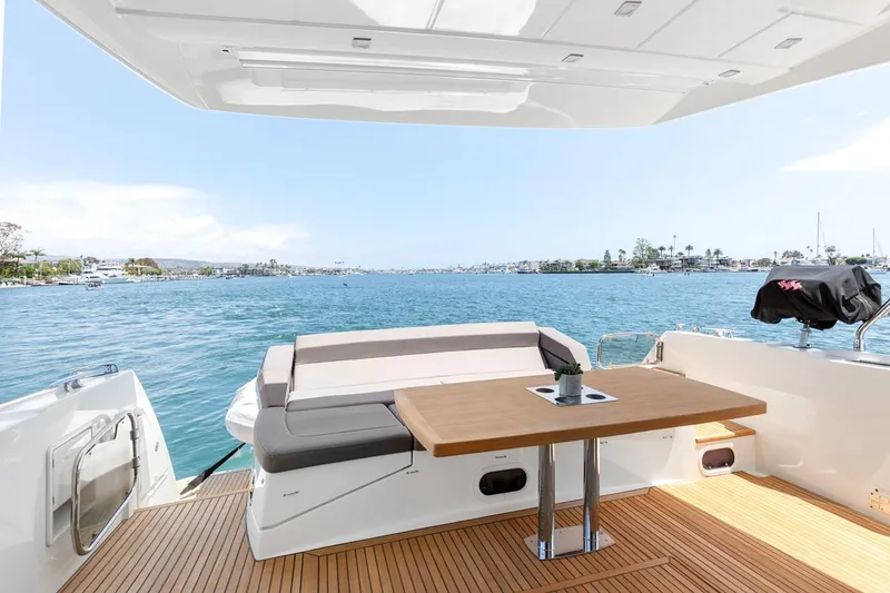 Slide: The Image of Prestige 550 yacht deck with seating and table, overlooking serene blue waters, 2016 model. - 6
