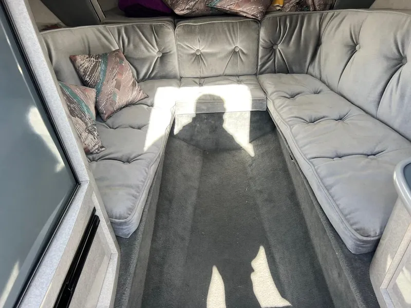 Slide: The Image of Interior of 1994 Checkmate 253 Convincor with gray tufted seating and decorative pillows. - 15