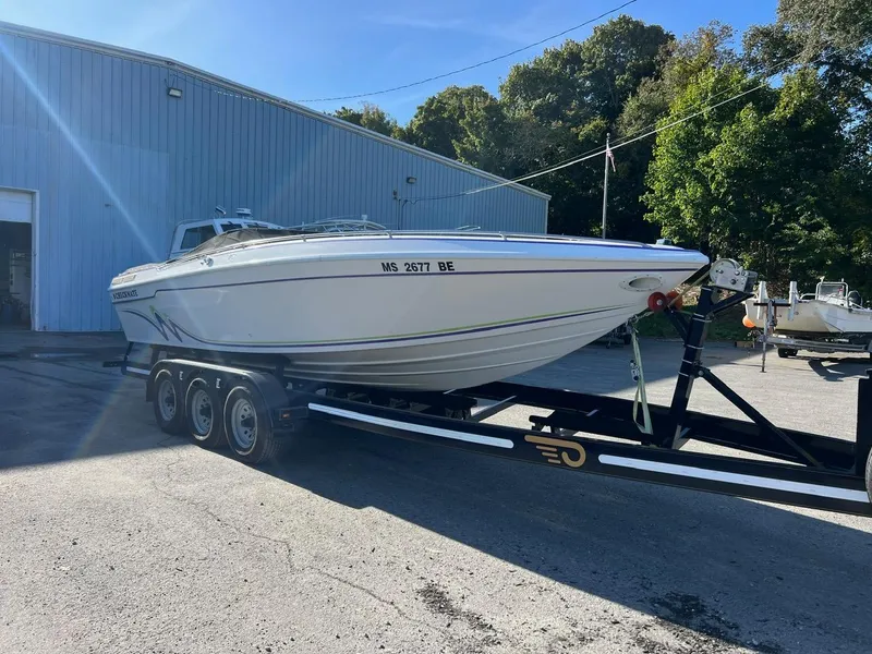 Slide: The Image of 1994 Checkmate 253 Convincor boat on trailer, parked outside a blue building. - 2