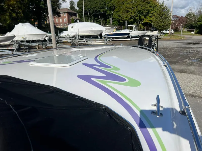 Slide: The Image of 1994 Checkmate 253 Convincor boat with colorful graphics, parked in a marina. - 7