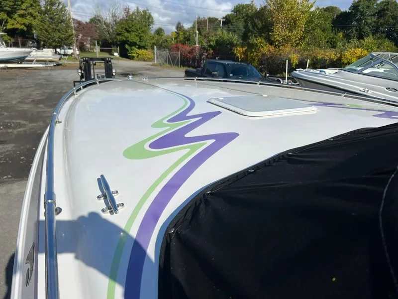 Slide: The Image of 1994 Checkmate 253 Convincor boat with colorful graphics, docked outdoors. - 8