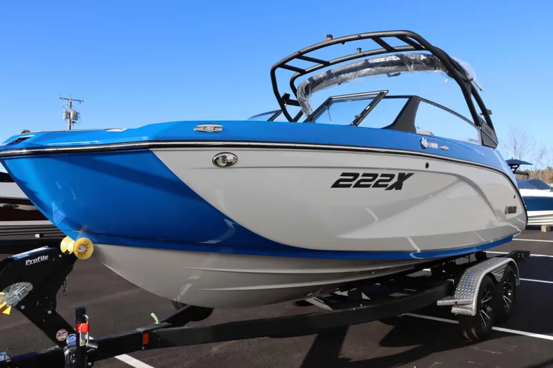 Slide: The Image of 2025 Yamaha Boats 222XD, blue and white, on trailer in parking lot. - 6