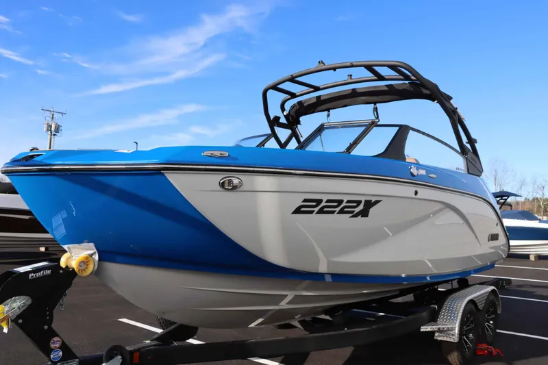 Slide: The Image of 2025 Yamaha Boats 222XE, blue and white, on trailer, under clear sky. - 3