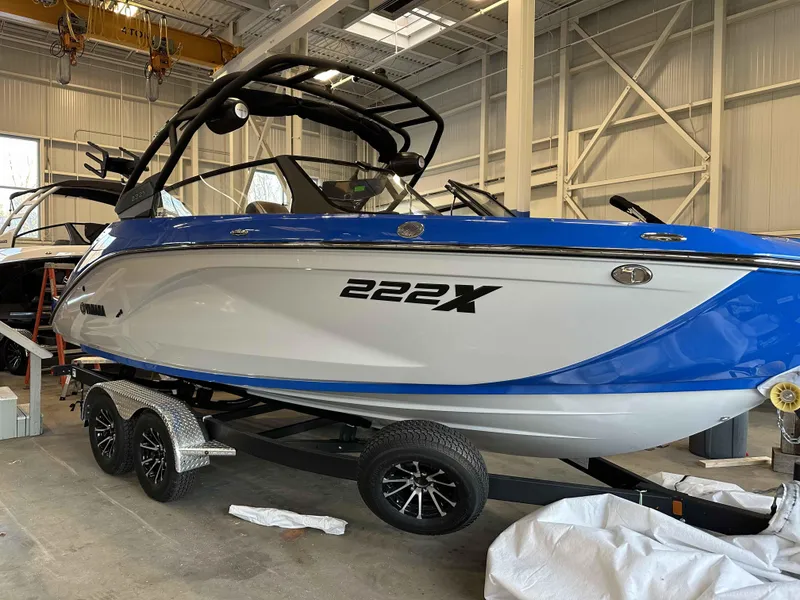 Slide: The Image of 2025 Yamaha Boats 222XE in a showroom, blue and white design on a trailer. - 6