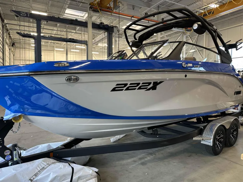 Slide: The Image of 2025 Yamaha Boats 222XE in showroom, blue and white design on trailer. - 7